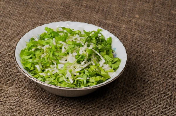 Cabbage salad in a plate on a wooden table.