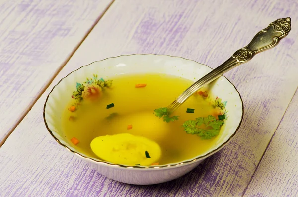 Clear soup with vegetables in plate on wooden table .Rustic styl