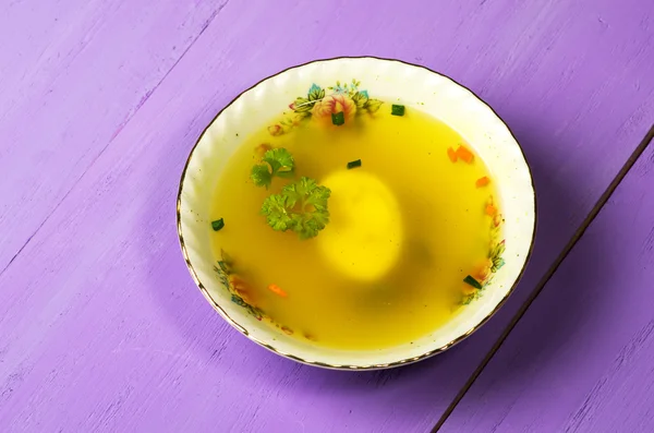 Clear soup with vegetables in plate on wooden table .Rustic styl