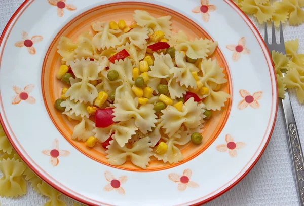 Pasta with corns, peas, tomatoes and spice on the white tablecloth