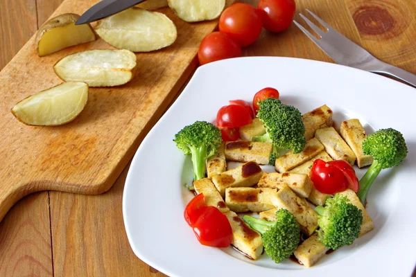 Pieces of roasted tofu with broccoli, tomatoes and soy sauce