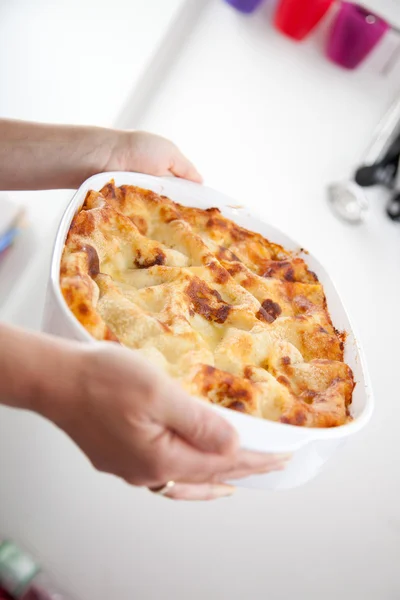 Woman holding a lasagna in the kitchen
