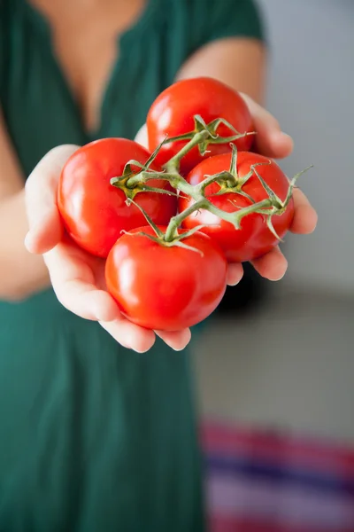 Woman holding tomatoes in her hand in the kitchen.