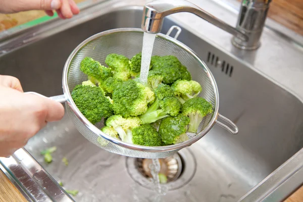 Woman washing broccoli in the kitchen sink