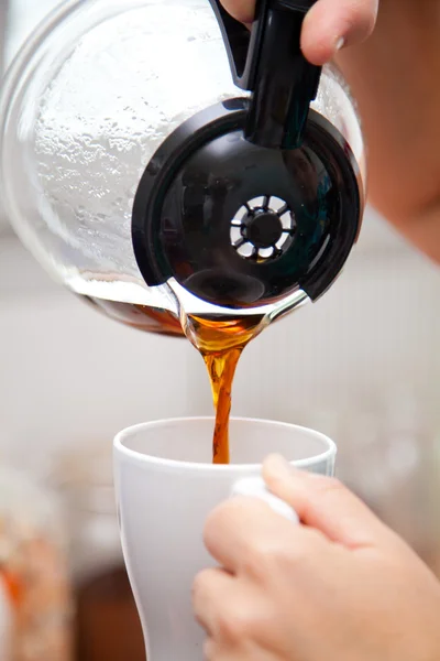 Woman pouring coffee pot  into coffe mug
