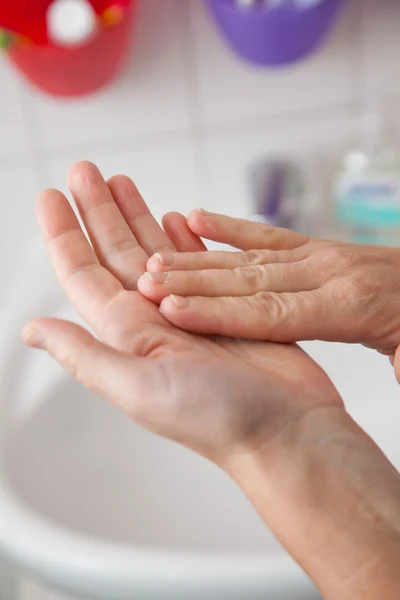 Woman creaming her hand with lotion in the bathroom