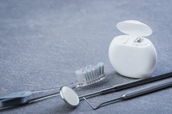 Basic dental tools, floss and brush on grey surface