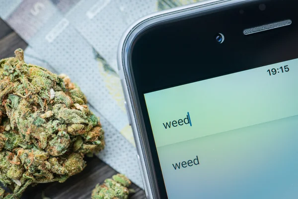 Phone, money and weed on a rustic wooden board