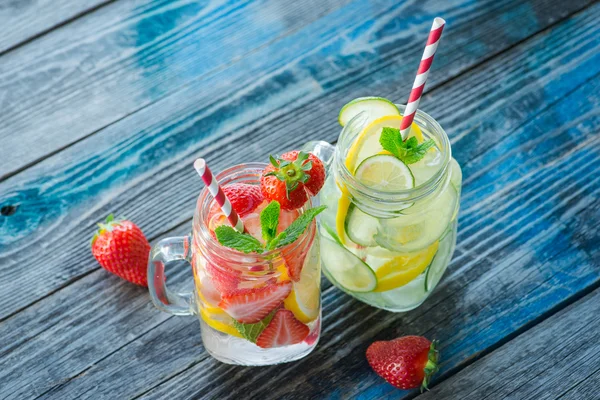 Jugs with lemon, lime and strawberry infused water on a rustic wooden surface