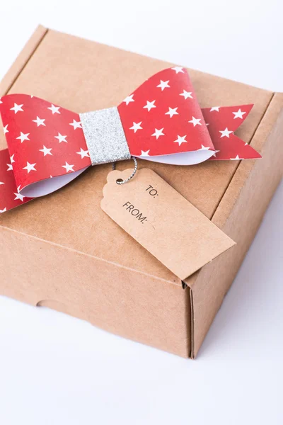 Brown cardboard gift box with a red bow and tag