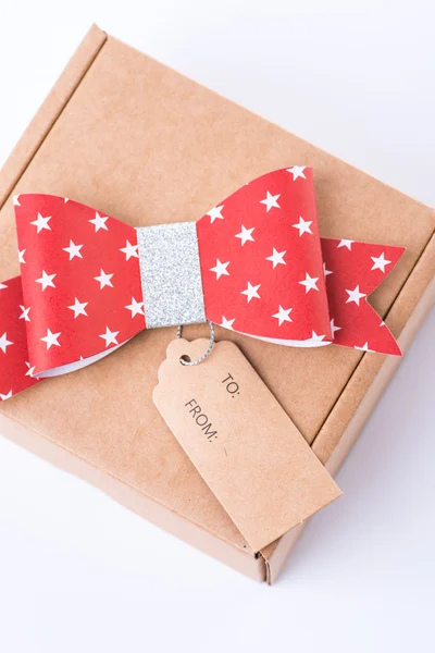 Brown cardboard gift box with a red bow and tag