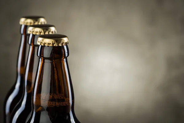 Freshly brewed beer bottles in a row over the grey concrete wall