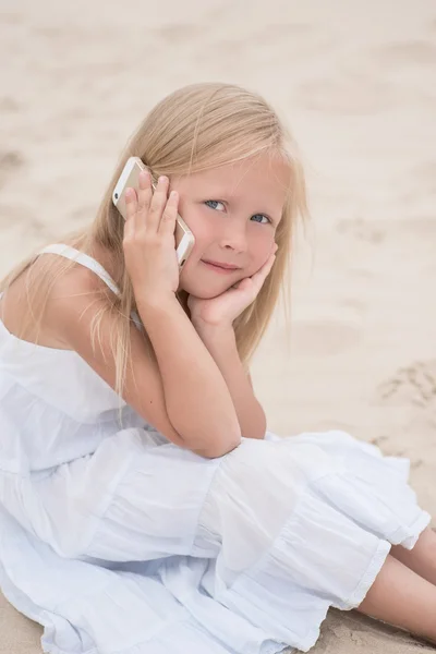 Beautiful young girl talking on the phone at the seaside