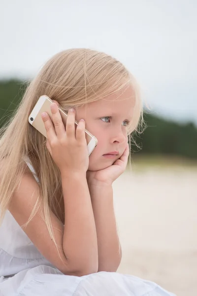 Beautiful young girl talking on the phone at the seaside