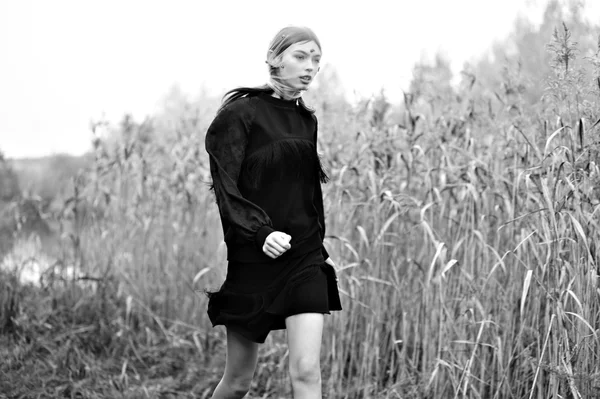 Fashion model woman run in black dress. Nature background.