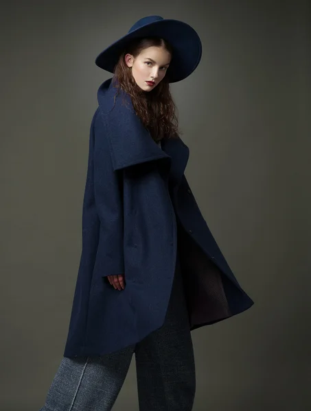 Fashion model woman coat and hat urban style pose on color background in studio