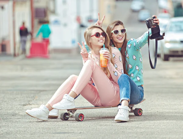 Hipster girlfriends taking a selfie in urban city context - Concept of friendship and fun with new trends and technology - Best friends eternalizing the moment with camera