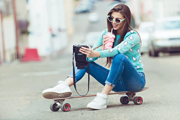 Beautiful young woman posing with a skateboard, fashion lifestyle at sunset