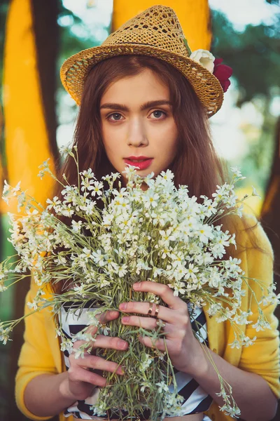 Hipster fashion girl in straw hat keep beauty flowers