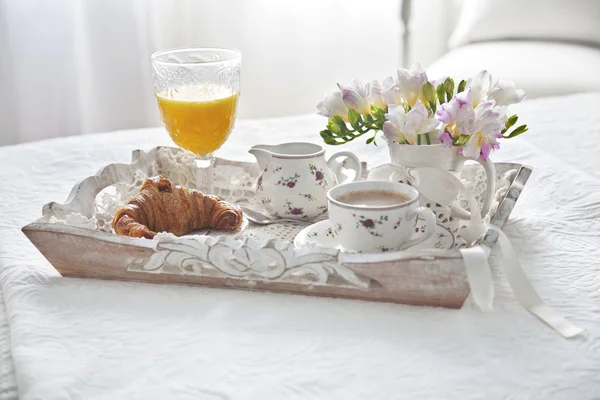 Croissant and tea with juice  on breakfast tray