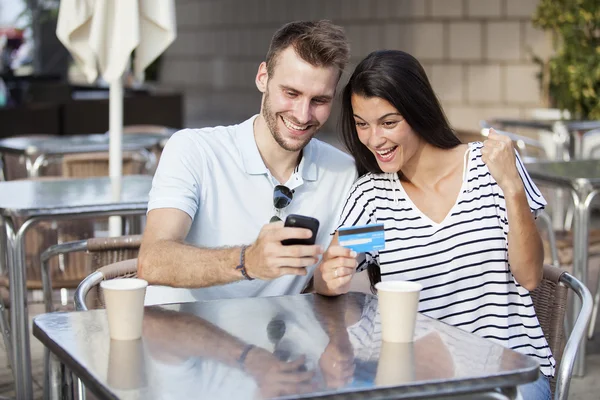 Couple buying online on holidays with a laptop and credit card on terrace bar