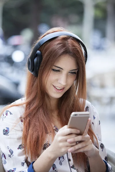 Gorgeous female enjoying recreation time while listen some music with her mobile phone on terrace bar