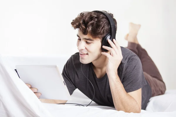 Happy man enjoying music through headphone on digital tablet