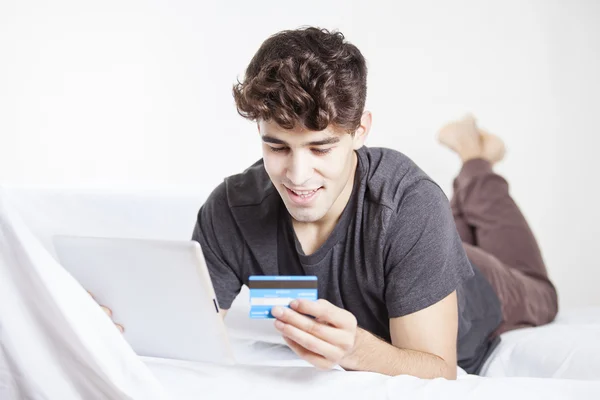 Casual young man doing online shopping through digital tablet and credit card