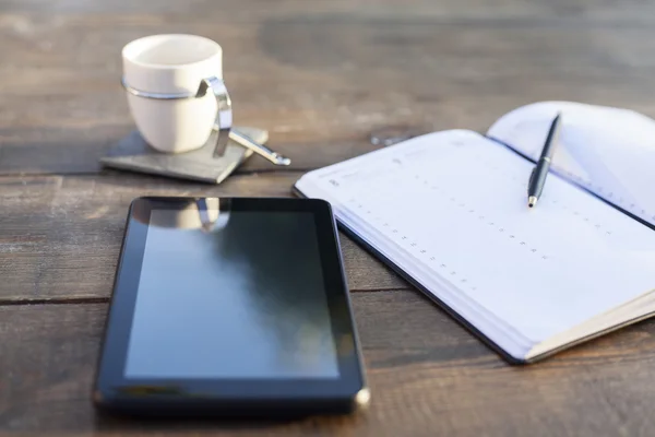 Digital tablet, coffee and note book on wooden table
