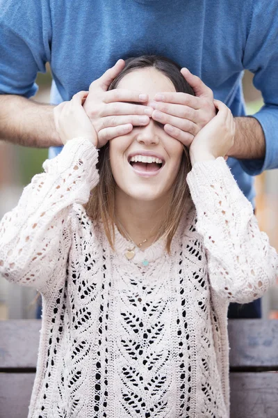 Man covering with hands eyes of young beautiful woman