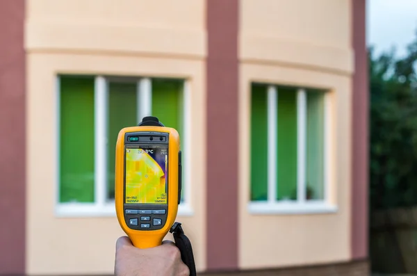 Man inspects house with thermal imaging camera