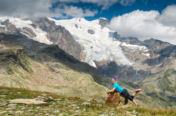 Woman hiker lying on the rock beside Alp glacier, Italy