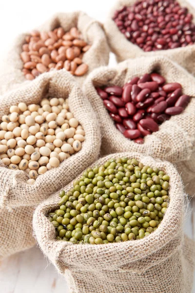Assortment of beans and lentils in hemp sack on wooden backgroun