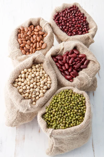 Assortment of beans and lentils in hemp sack on wooden backgroun