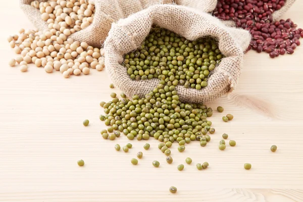 Assortment of beans and lentils in hemp sack on wooden backgroun