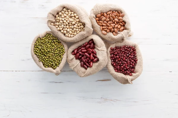 Assortment of beans and lentils in hemp sack on wooden backgroun