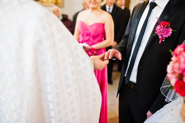 Priest wears a wedding ring on the hand of the groom