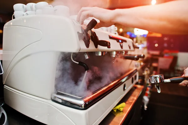 Professional barman at coffee machine with vapor making espresso