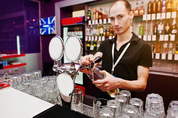 Bartender pours a beer at the bar in the club