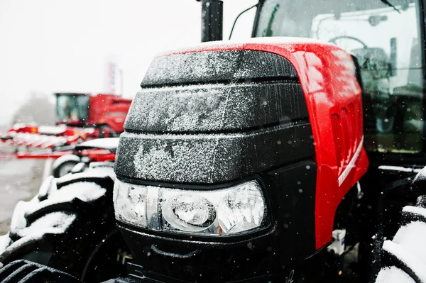 Close up in front of the new red tractor at snowy weather