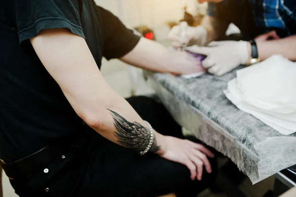 Tattoo master make tattoo for rocker man at tattoo salon