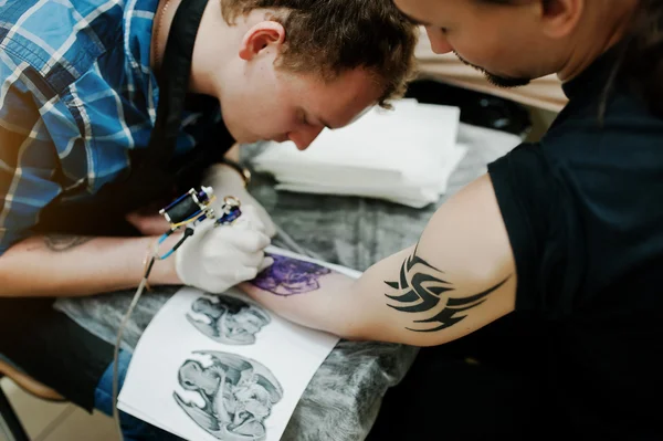 Tattoo master make tattoo for rocker man at tattoo salon