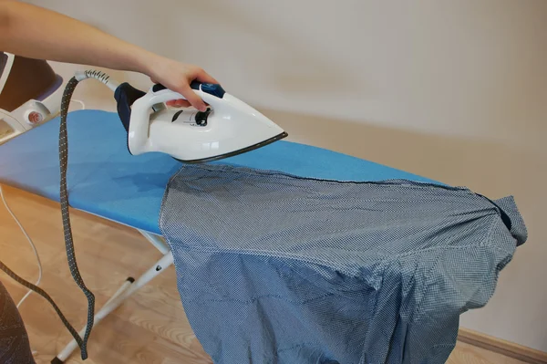 Hand of woman on ironing board with steam iron system