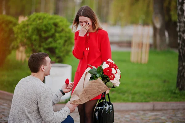 Marriage proposal. Man with boquet of flowers kneeling and give