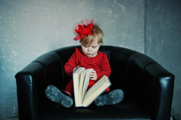 Little cute princess girl sitting on a chair and read old book