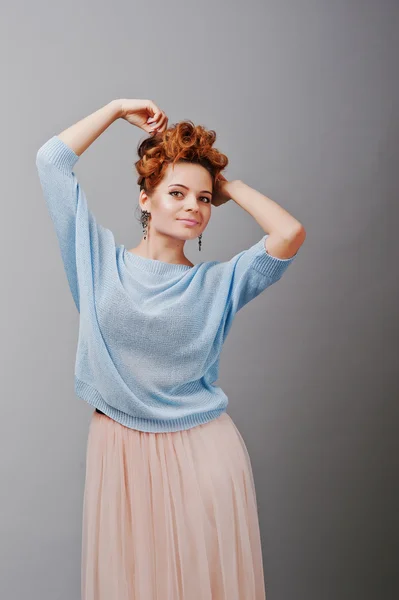 Studio portrait of young red haired curly girl at blue blouse an