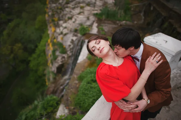 Couple hugging in love background fantastic cliff with waterfall