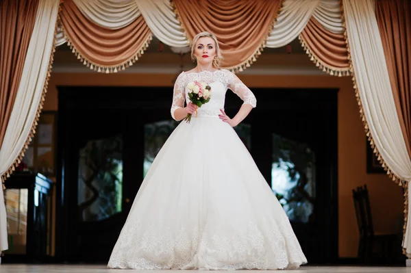 Gorgeous blonde bride posed indoor great wedding hall background