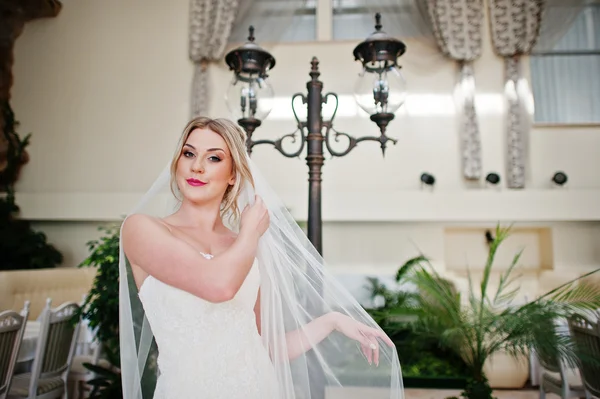 Gorgeous blonde bride with long veil posed at great awesome wedd