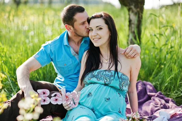Happy pregnant couple at turquoise dress on the garden
